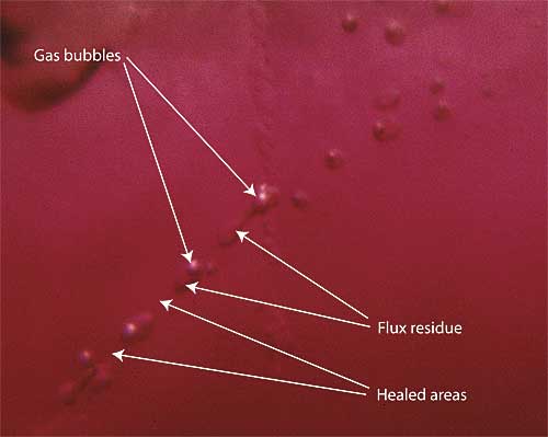 Figure 10. Flux residue may be two-phase Highly magnified photo showing flux residue within a flux-healed Mong Hsu ruby. Note that the small flux-filled pockets may contain gas bubbles formed by contraction of the flux residue as it cools. Photo: R.W. Hughes