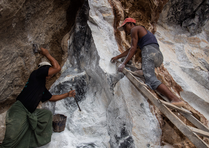 Figure 3. Ruby miners preparing to set an explosive charge in the marble at Sagyin, just north of Mandalay. Note the clay band cutting through the marble. Hydrothermal fluids from this clay are thought to have supplied the aluminum and chromium necessary for the growth of ruby and spinel in marble. Photo: E. Billie Hughes