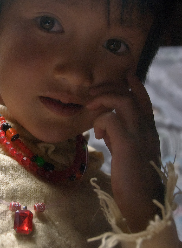 Why travel? Let us answer that riddle with a picture. The gem is a piece of ordinary red glass, worth perhaps a dollar. But gaze into this Kyrgyz' girl's eyes and you will find discover priceless treasure. Gems are accessories. Life and living is about people. Photo: Richard W. Hughes
