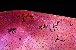 This synthetic pink sapphire was fractured and then appeared to have been soaked in an iron-rich solution to created orange stains in the fissures, thus simulating padparadscha. The stains developed unusual dendritic patterns, as seen here. Chemical analysis also reveal traces of lead in the fissures.