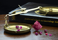 Ruby and spinel crystals, along with al-Biruni's book on precious stones