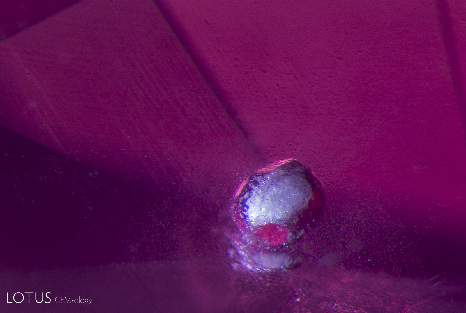 This melted crystal shows a “frosty” appearance similar to that of a snowball. The vast majority of spinels that we see in our lab are untreated, but this is a rare example of a heated spinel. The host of this melted crystal is a Mahenge, Tanzania, spinel. Darkfield + Diffuse oblique fiber optic illumination. Photo: E. Billie Hughes