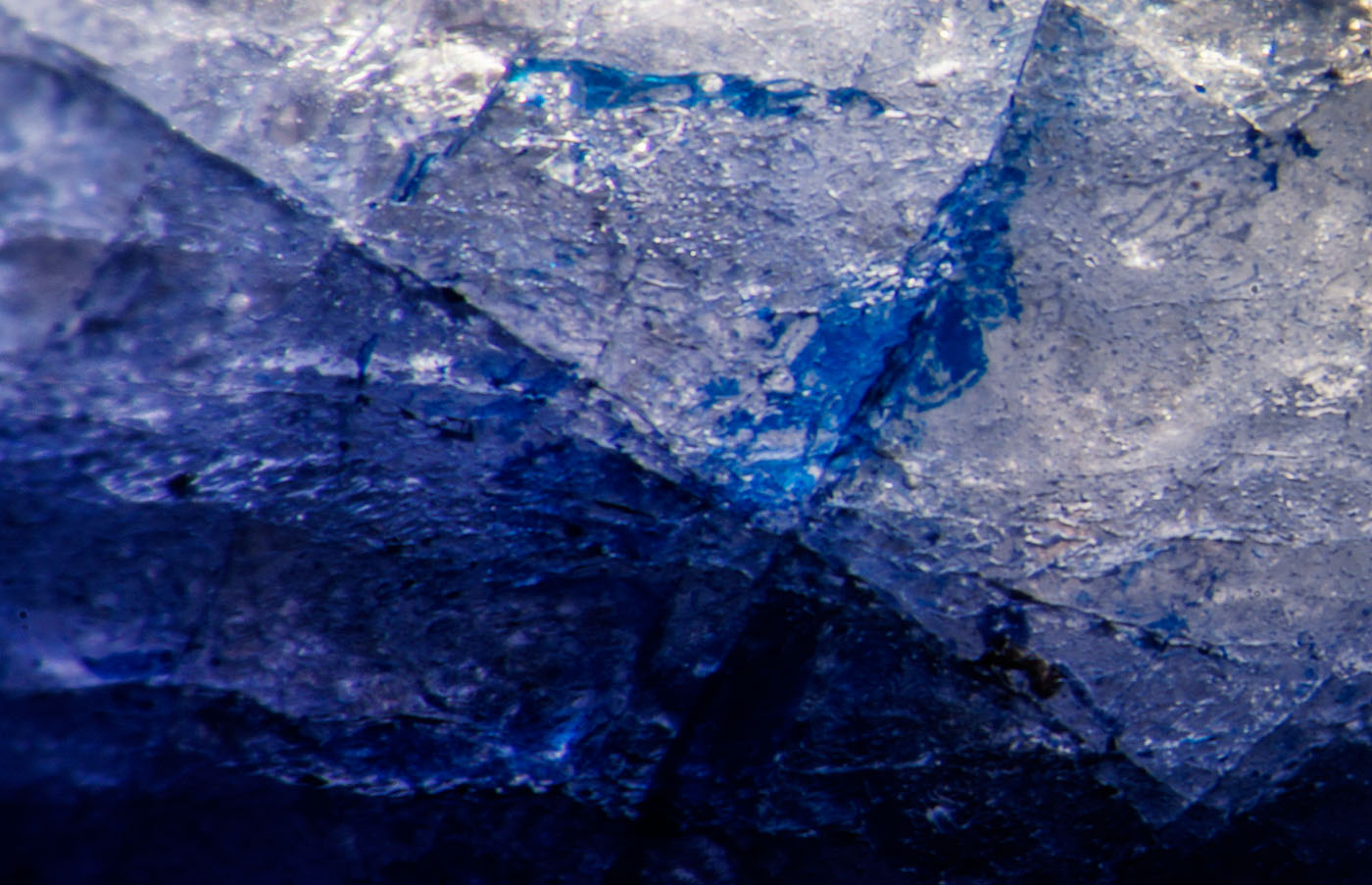 Figure 6. Blue cobalt-doped glass fills a surface-reaching fissure in this first-generation stone. Oblique fiber-optic illumination. Photo: Wimon Manorotkul