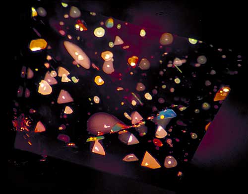 Figure 7. …equals inner triangulation Decrepitation halos surround minute primary negative crystals in the pinacoidal plane of a basaltic Thai/Cambodian ruby, creating a sea of highly characteristic thin-film fluid inclusions. One can clearly see the three-fold symmetry of these distinctive features. Photo © Richard W. Hughes