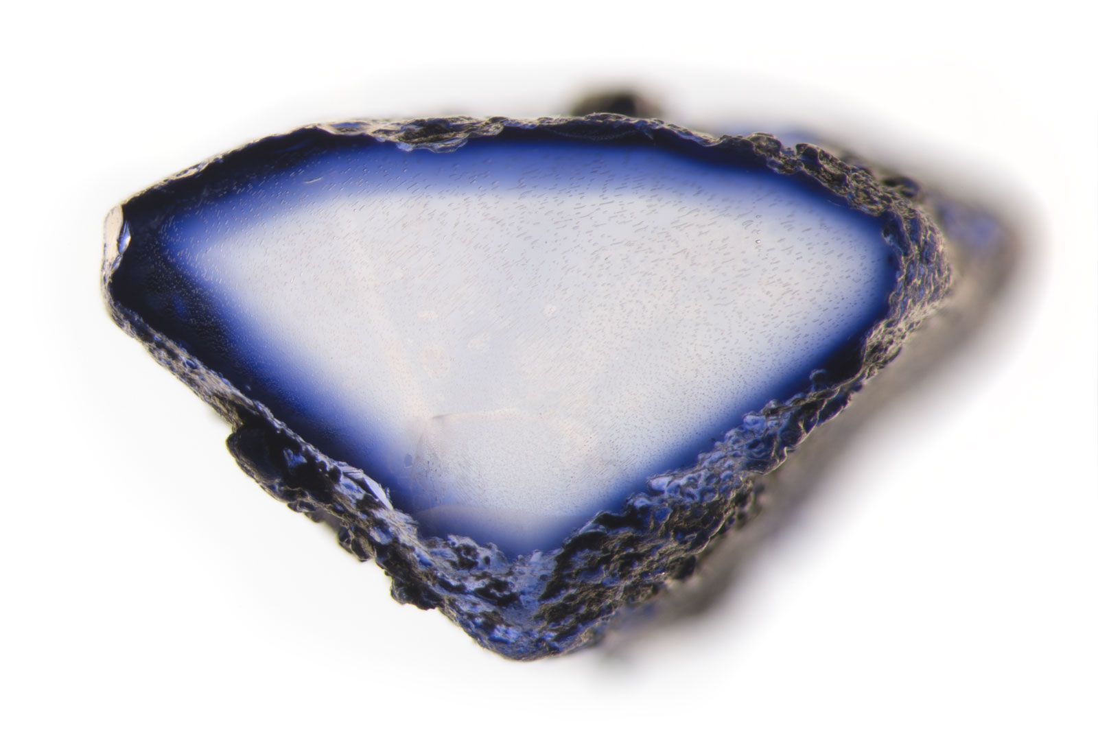 Near colorless sapphire that was lattice-diffused with titanium (Ti) that has been sliced through to show the depth of penetration of the chromophore. Because the chromophore added from outside the stone and because recutting the stone could produce loss of color, this treatment requires special disclosure.