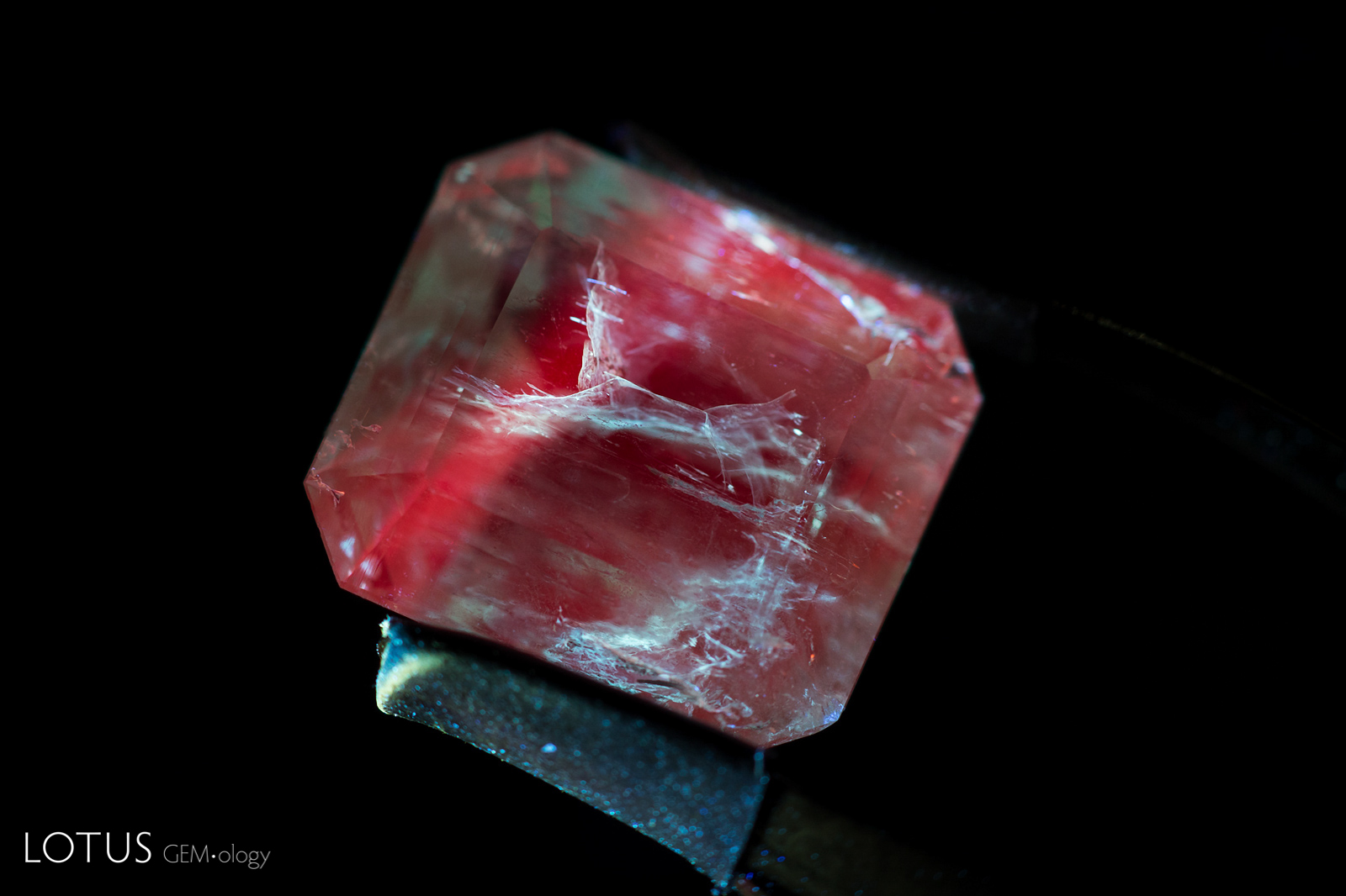 Figure 2. When viewed with the Covoy S2+ torch, this Colombian emerald displays a red fluorescence. However, the fissures display a chalky blue reaction because the filler in the fissures is fluorescing as well. Photo: E. Billie Hughes/ Lotus Gemology