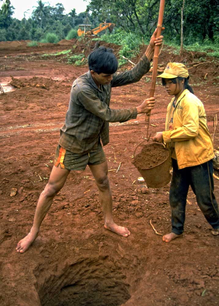 Pit miners at Khao Ploi Waen, ca. 1980. While the mine was real, the cut stones being sold just off camera were anything but, consisting of doublets made of thin slices of natural green sapphire on top of Verneuil synthetic corundum. Photo: Richard W. Hughes
