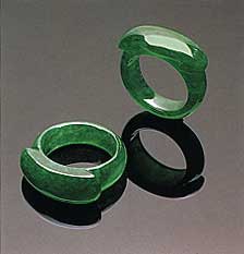 Figure 8. Note the small patches of a slightly paler color on the shank of one of these "emerald" green saddle rings (21.27 and 21.65 mm, respectively, in longest dimension). Photo courtesy of and © Christie's Hong Kong and Tino Hammid.