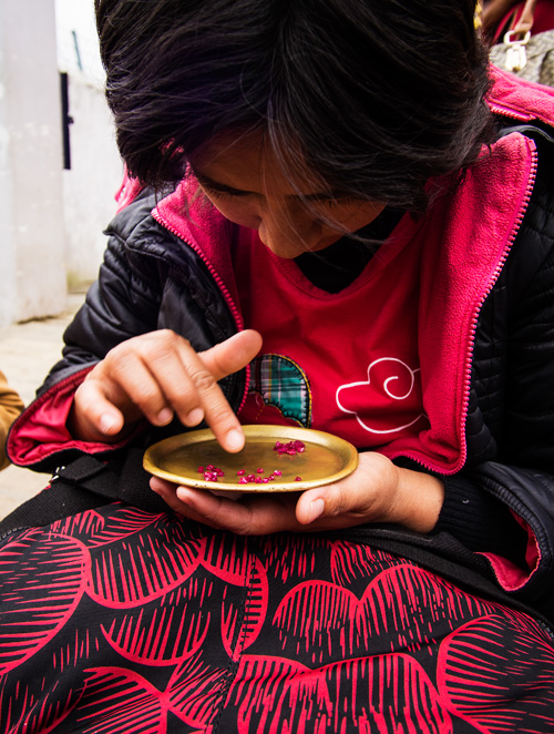 Figure 6. A woman sorts stones in Mogok’s market. Brass trays were originally used to enhance the color of red stones, but have become so ubiquitous that now buyers bring their own brass trays. Photo: E. Billie Hughes