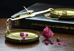 Ruby and spinel crystals, along with al-Biruni's book on precious stones