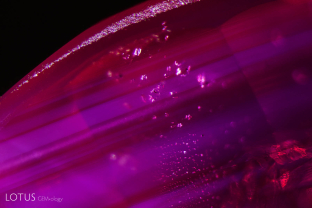 Zoned clouds of fine exsolved particles creating a milky appearance, along with a fingerprint made up of coarse negative crystals.