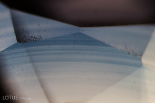 Curved growth lines and small gas bubbles are visible in this Verneuil synthetic sapphire. The curved lines are a diagnostic feature of Verneuil synthetic corundum. Note that the facets have some rough areas, an indicator that a stone was hastily polished.