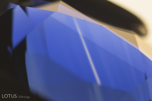 This image clearly illustrates what master photomicrographer John Koivula has termed “chromophore cannibalization.” As titanium is drawn out of solid solution to form exsolved rutile silk, the area in the vicinity is decolorized, losing its blue color. This is a natural process and is the reverse of “internal diffusion,” where heat treatment sends the titanium back into solution, creating blue clouds or “inkspots” around the rutile remnants.