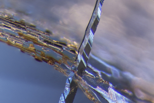 ‘Scuse me while I pierce the sky. A negative crystal cuts through a fingerprint against a sky blue backdrop in this unheated Sri Lanka sapphire.