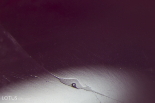 A narrow fissure has been filled with glass, shown by the duller luster of the glass when compared to the surrounding corundum. We can also see a round spot where a gas bubble popped in the glassy area.