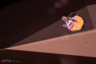 A clinochlore crystal in a spinel host displays a rainbow of interference colors when observed between crossed polars. When the polarizing plates are rotated the interference colors change.