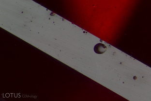Spall marks on the surface of this Mozambique ruby prove that it was heat-treated after cutting and polishing.